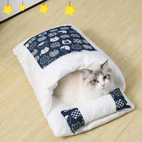 Chat blanc couché dans une couette fermée avec oreiller assorti, design bleu avec motifs de chats, offrant confort et chaleur.